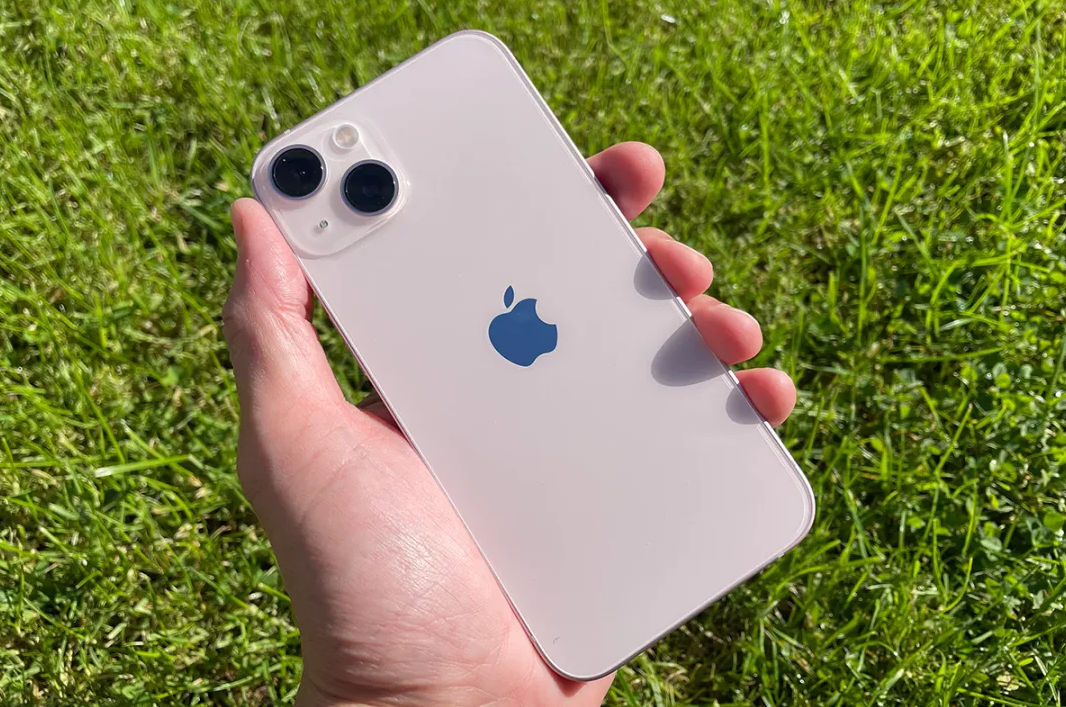 Iphone 13 storage, holding iphone 13 outside, grass background