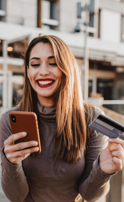 Fraud Prevention &Amp; Device Ownership Policy (For Trade Ins) Woman smiling with phone and bank card in hands
